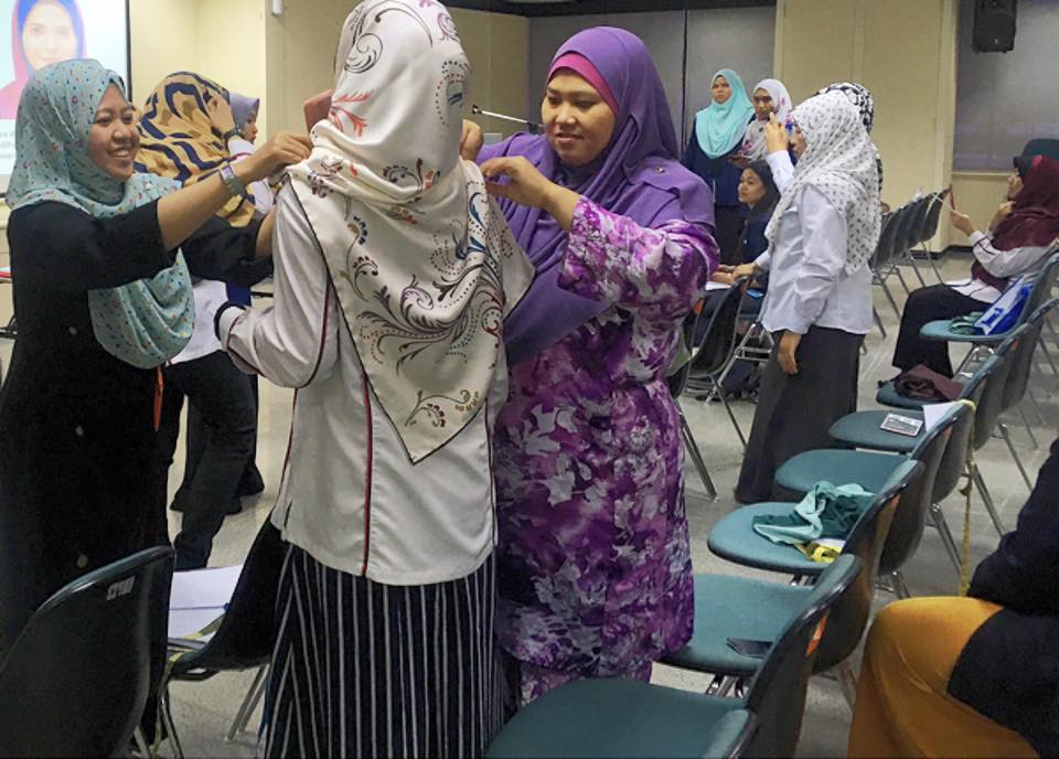 Para peserta membantu antara satu sama lain menggayakan 6 teknik stail hijab yang ditunjukkan.